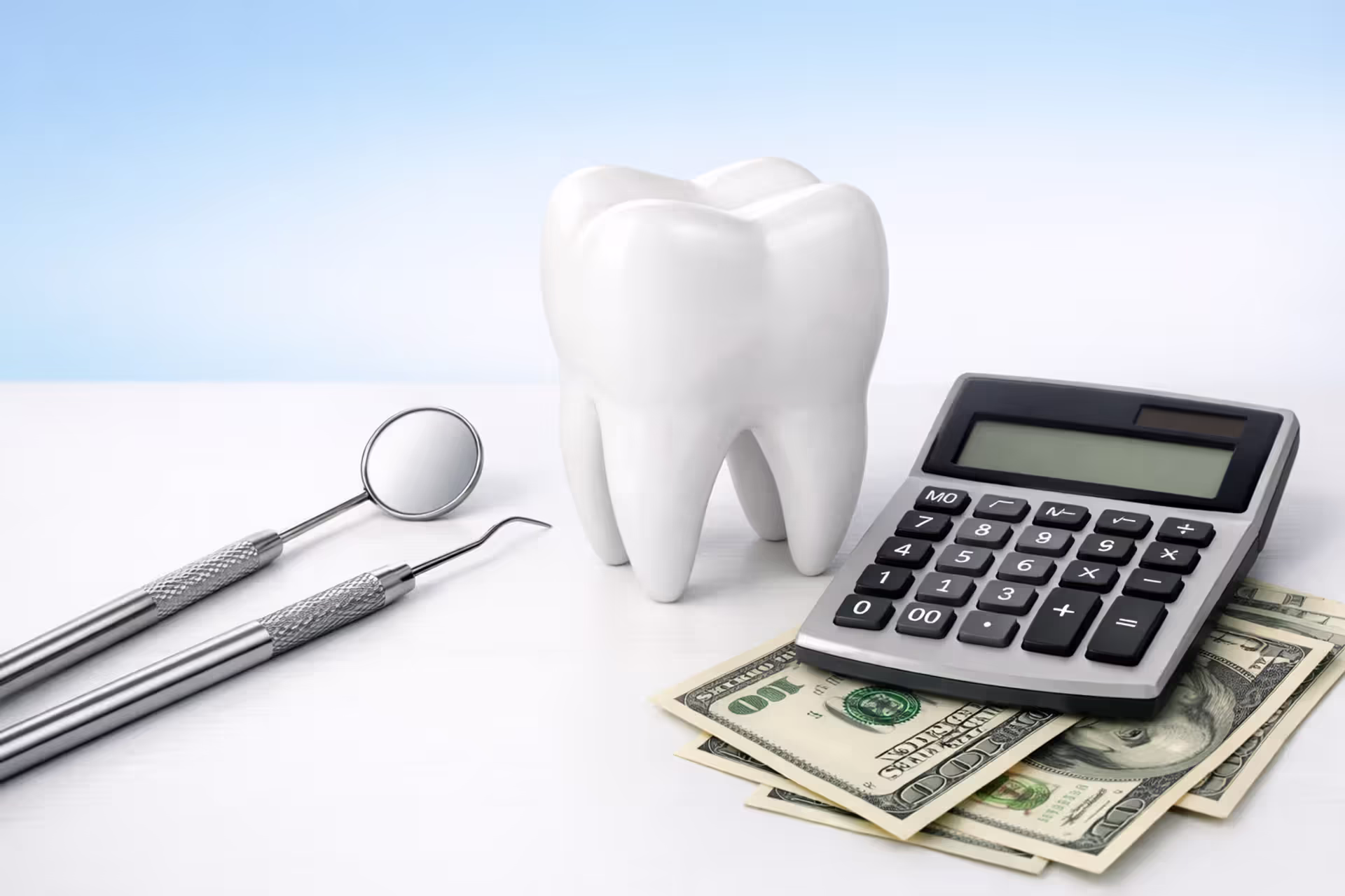 Dental tools, tooth model, calculator and dollar bills on a clean desk representing dental insurance costs
