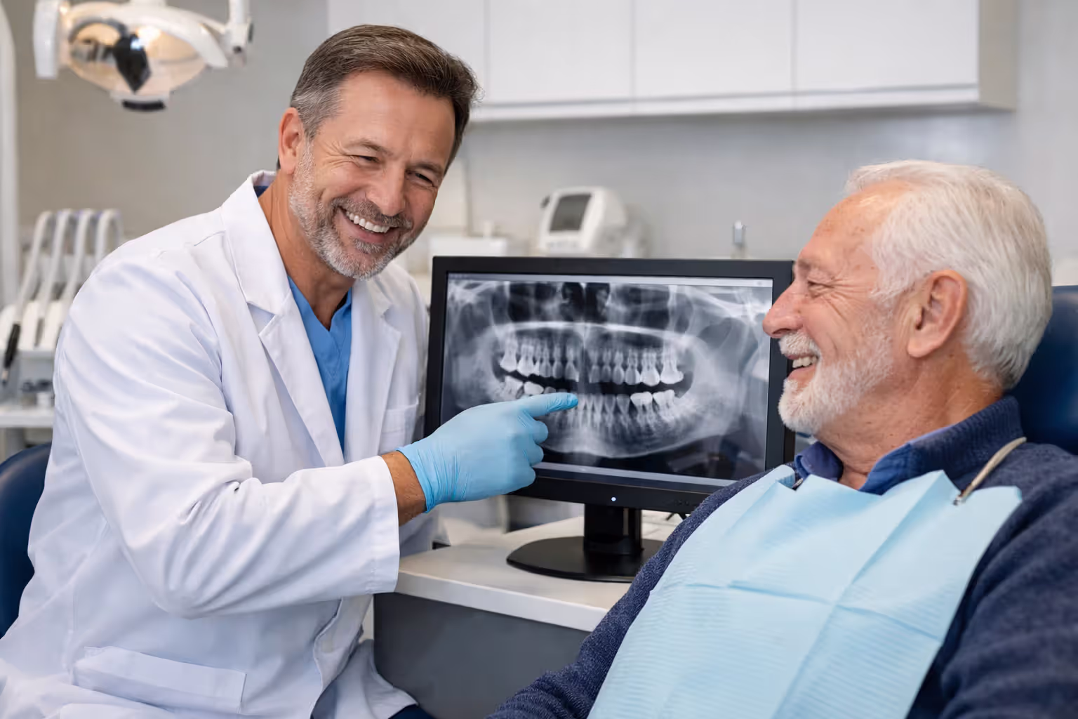 Dentist showing dental X-ray on screen to senior male patient in modern dental office
