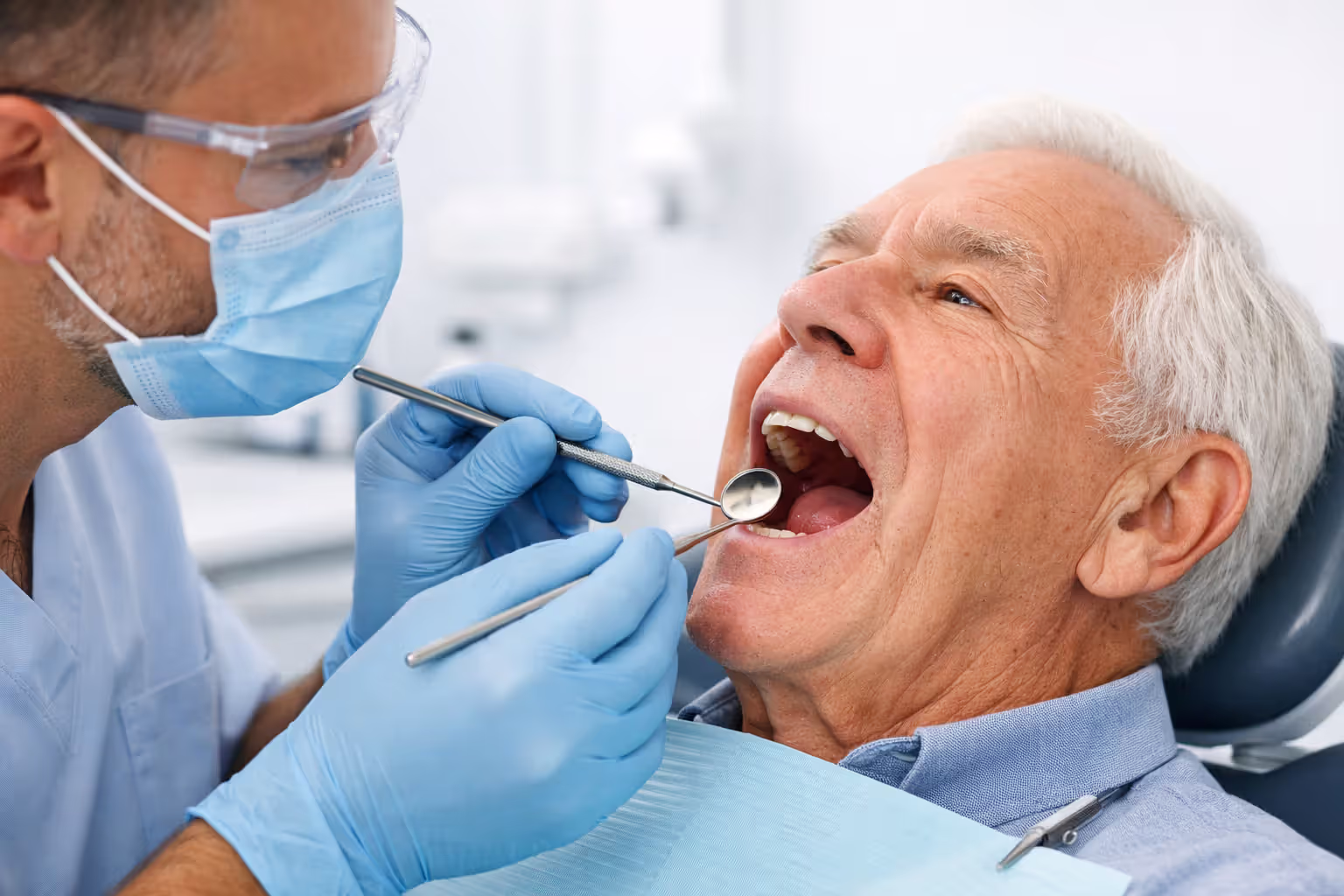 Dentist examining an elderly patient's teeth in a modern dental office
