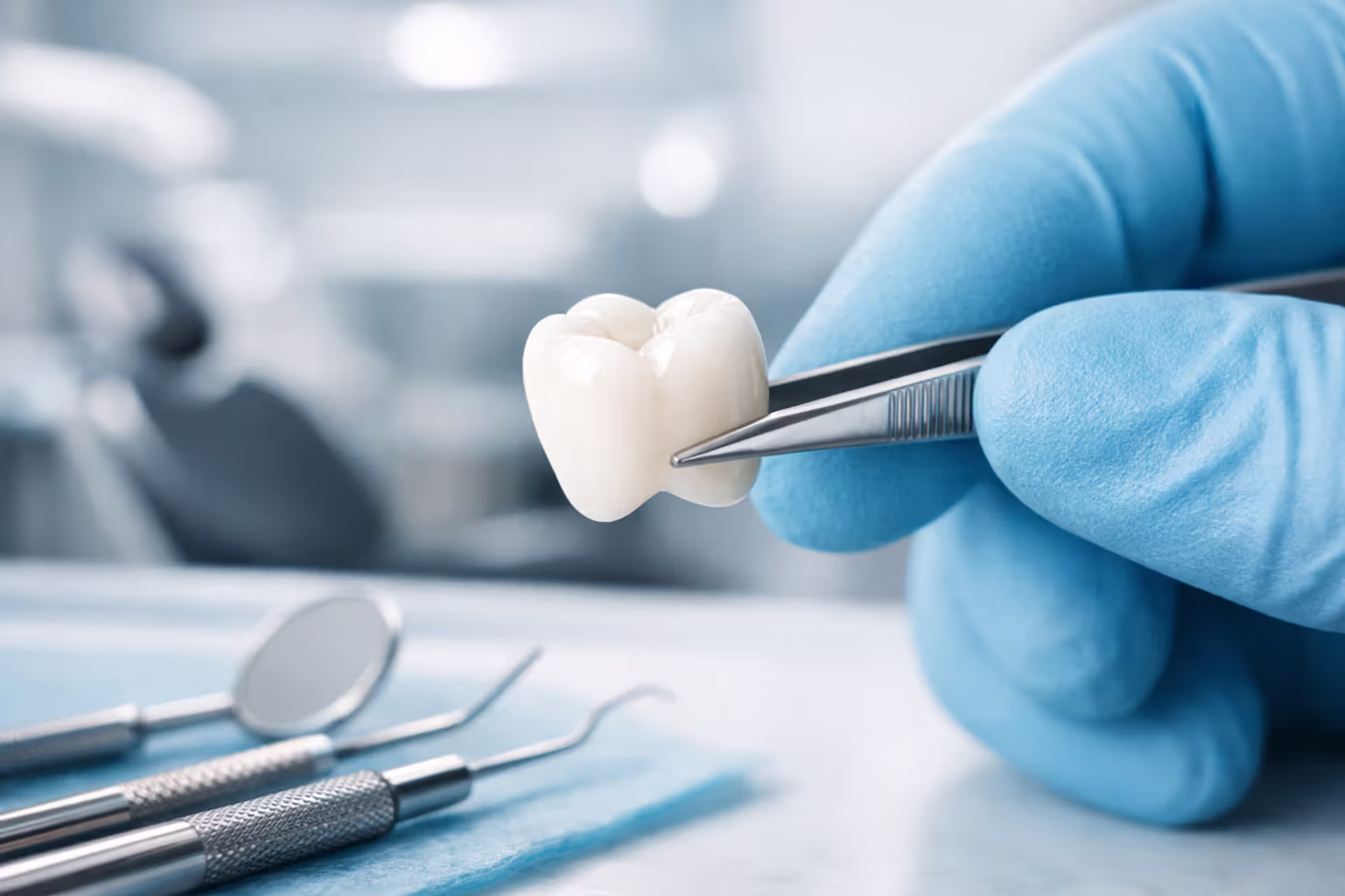 Close-up of a dentist holding a white ceramic dental crown with tweezers in a modern dental office